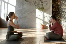 2 Frauen im Schneidersitz sitzen sich gegenüber, Atmen